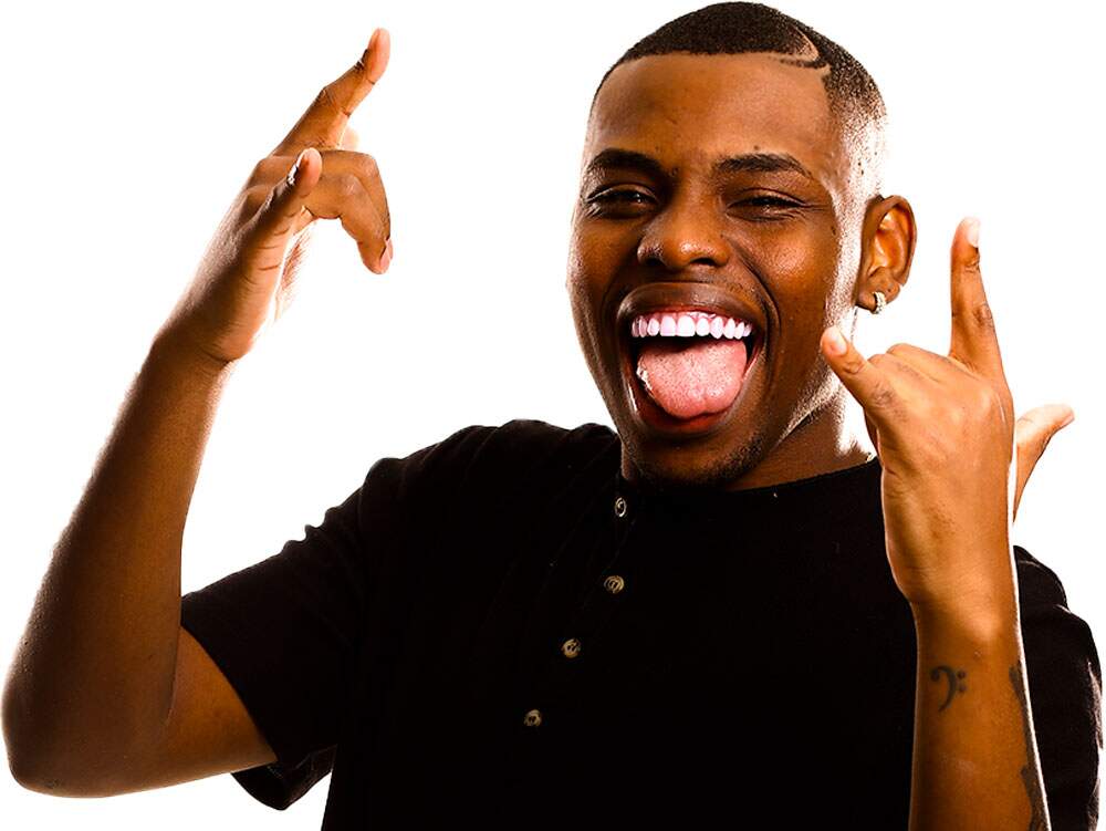 A imagem mostra o cantor Ricky Silva com sorriso aberto e a língua de fora, fazendo o símbolo do rock com as mãos. O rapaz usa uma calça preta com uma bandana pendurada do lado esquerdo e uma camiseta preta com quatro botões próximos à gola. Seu cabelo é raspado, com um corte em desenho circular do lado esquerdo.