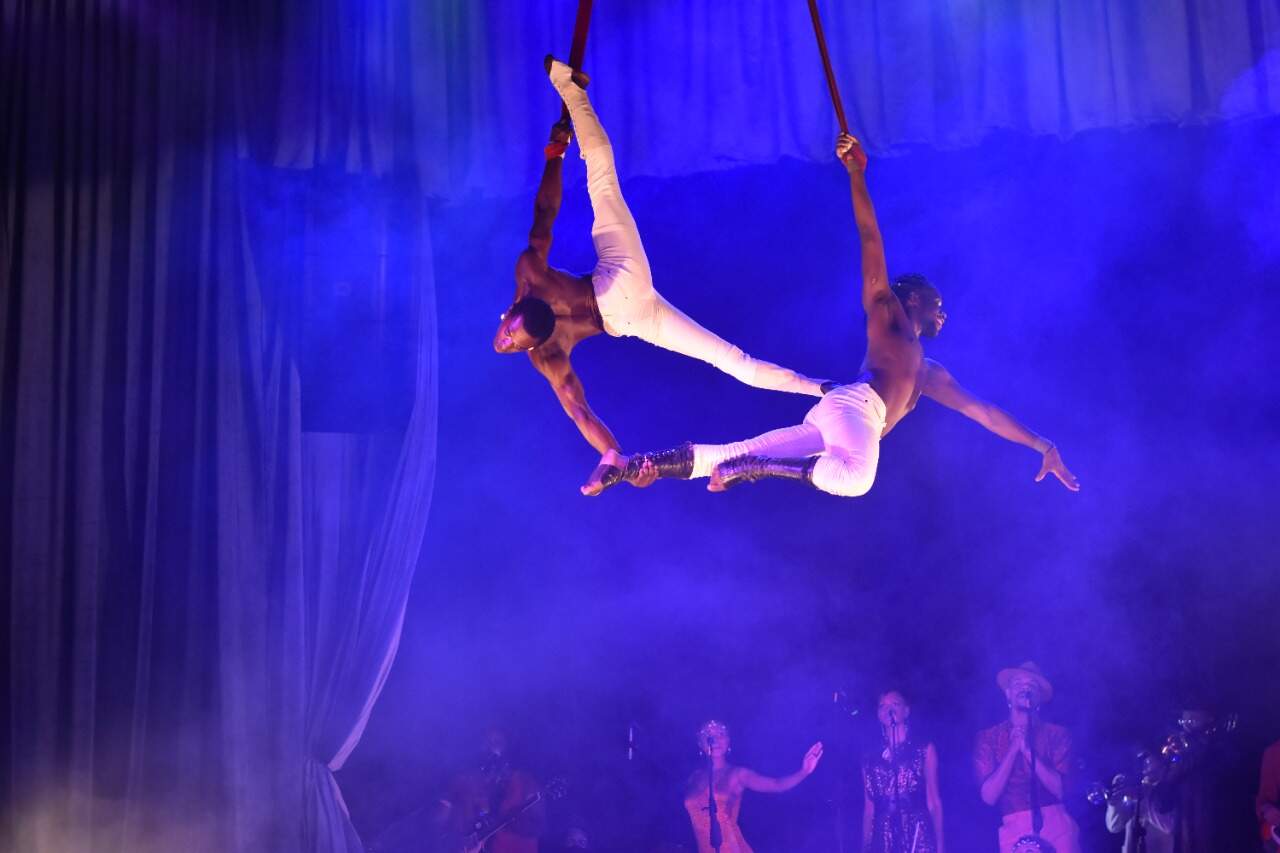 fotografia com o espetáculo circense, dois artistas estão se apresentando suspensos por cordas.