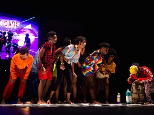 Grupo de jovem no palco com figurinos de diversas cores