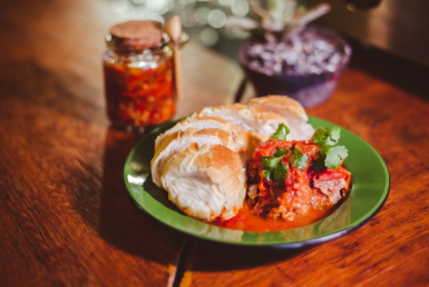 Foto de um prato com Carne suã mineira ao molho de tomate. Acompanhado de pão de sal.
