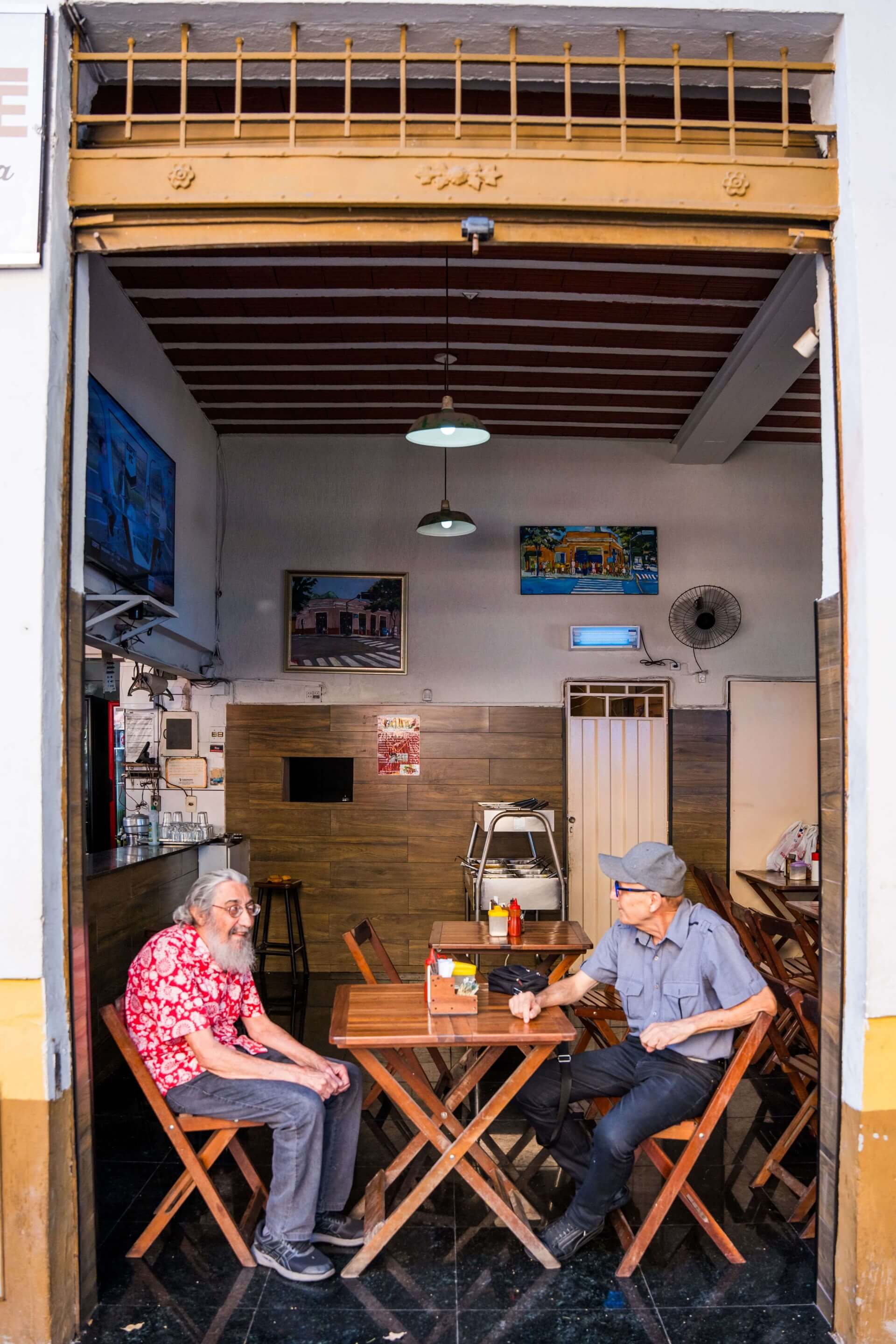 Imagem de dois senhores sentado em uma mesa de bar