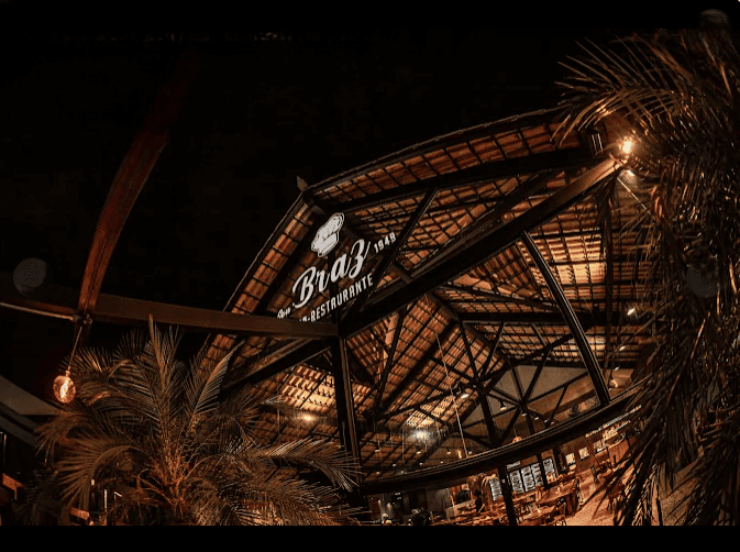 Imagem de uma bar, todo de madeira e palmeiras em volta.