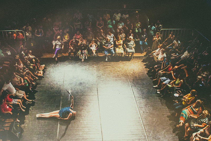 Imagem dos espaço cênico do teatro cheio enquanto acontece uma apresentação