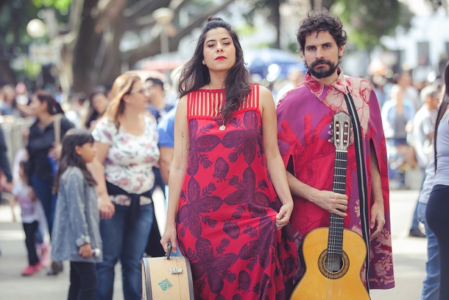 Um mulher ao lado de um homem segurando o seu violão