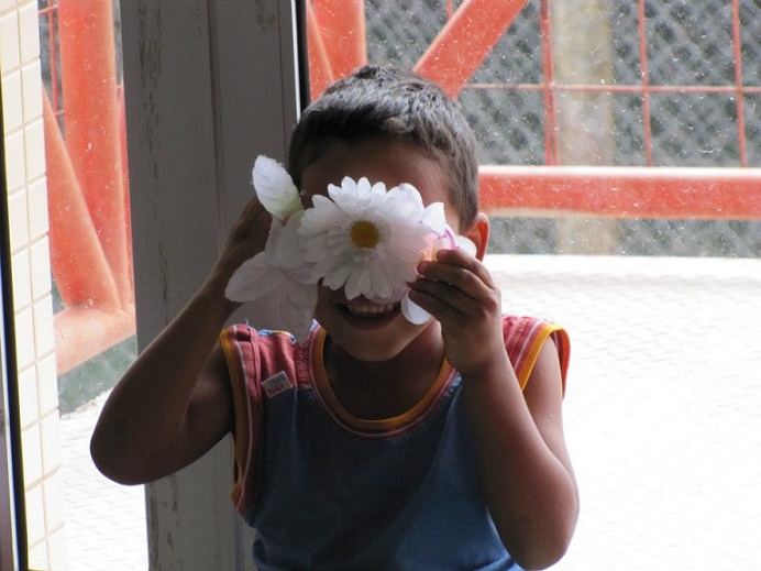 Criança segurando flores na frente de seus olhos 