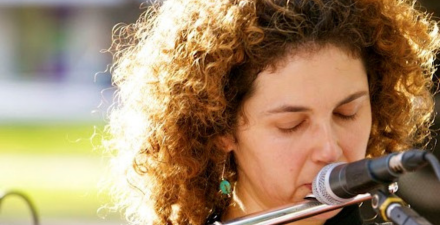 Mulher loira tocando flauta.