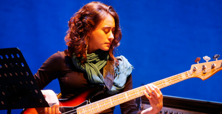 Foto de Camila Rocha sentada tocando uma guitarra. 