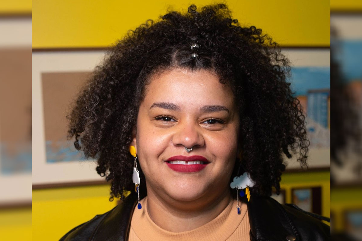 Mulher negra, jovem, sorrindo.