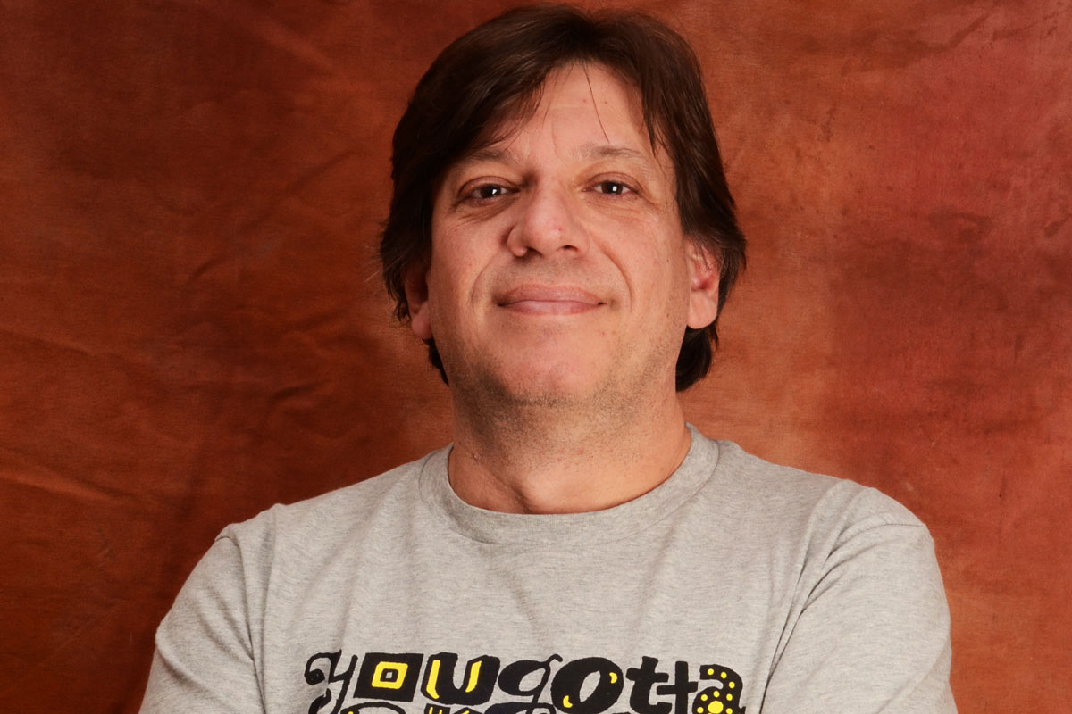 Fernando Rabelo Homem de pele clara, de braços cruzados, sorrindo discretamente.