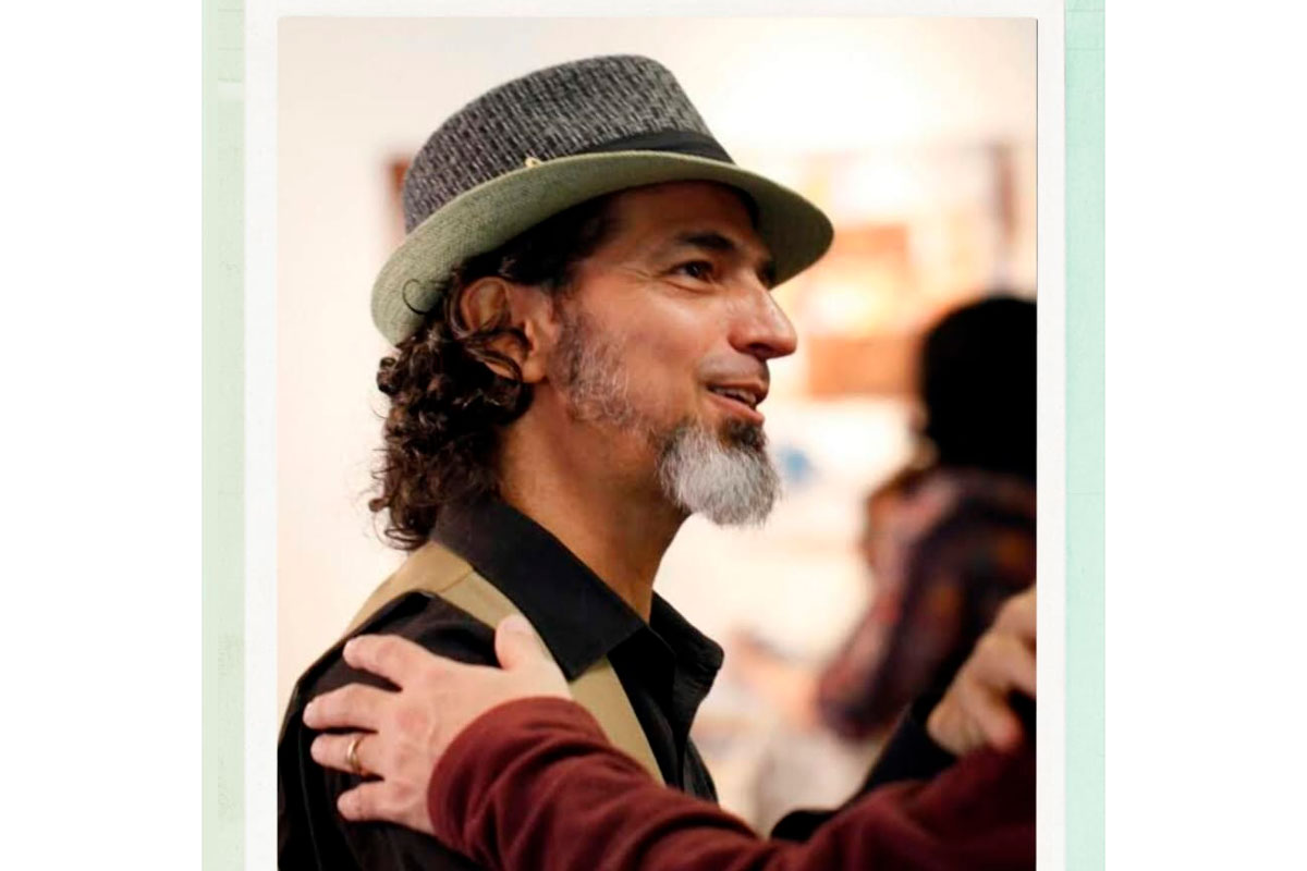 Homem de pele clara, barba branca e cabelos escuros, usando chapéu.