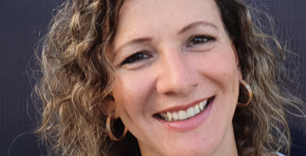 Mulher branca de olhos castanhos e cabelos loiros cacheados