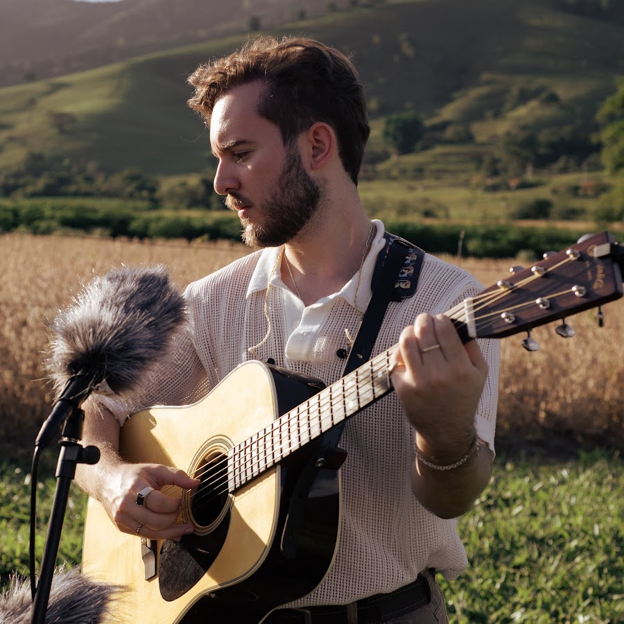 Imagem do cantor Rafael cantando com um violão