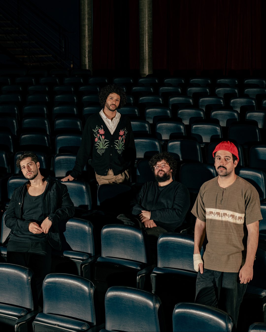Foto da banda Zimbra, 4 integrantes no cenário de uma sala de cinema
