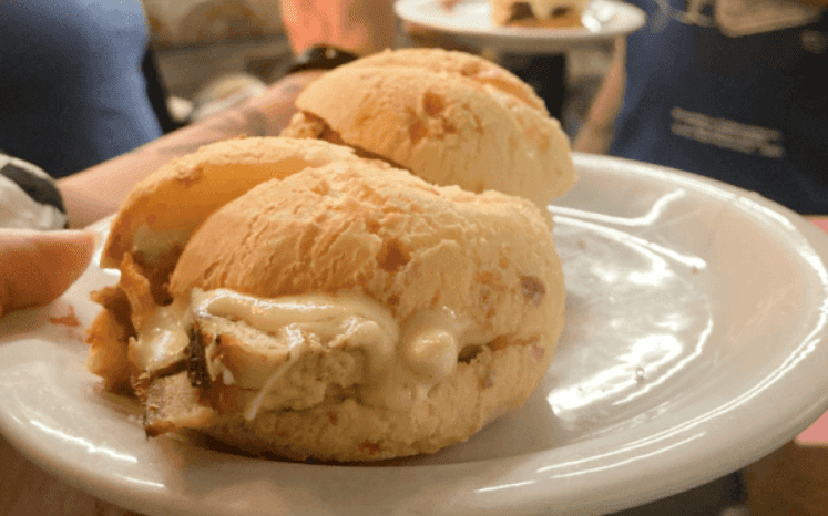 Foto de divulgação do evento "Minas é Muitas - experiência gastronômica nos Mercados de BH": Fotografia de três pães de queijo recheados com pernil desfiado e requeijão