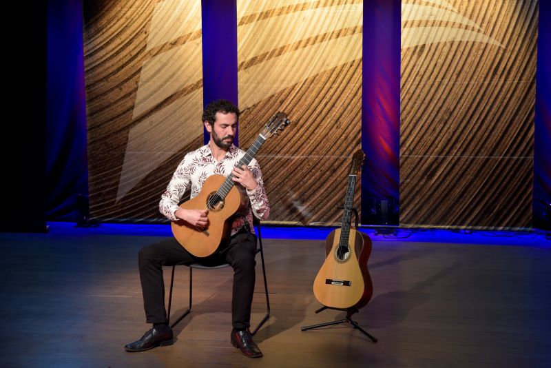 Foto do Gustavo Ramos no palco com dois violões.
