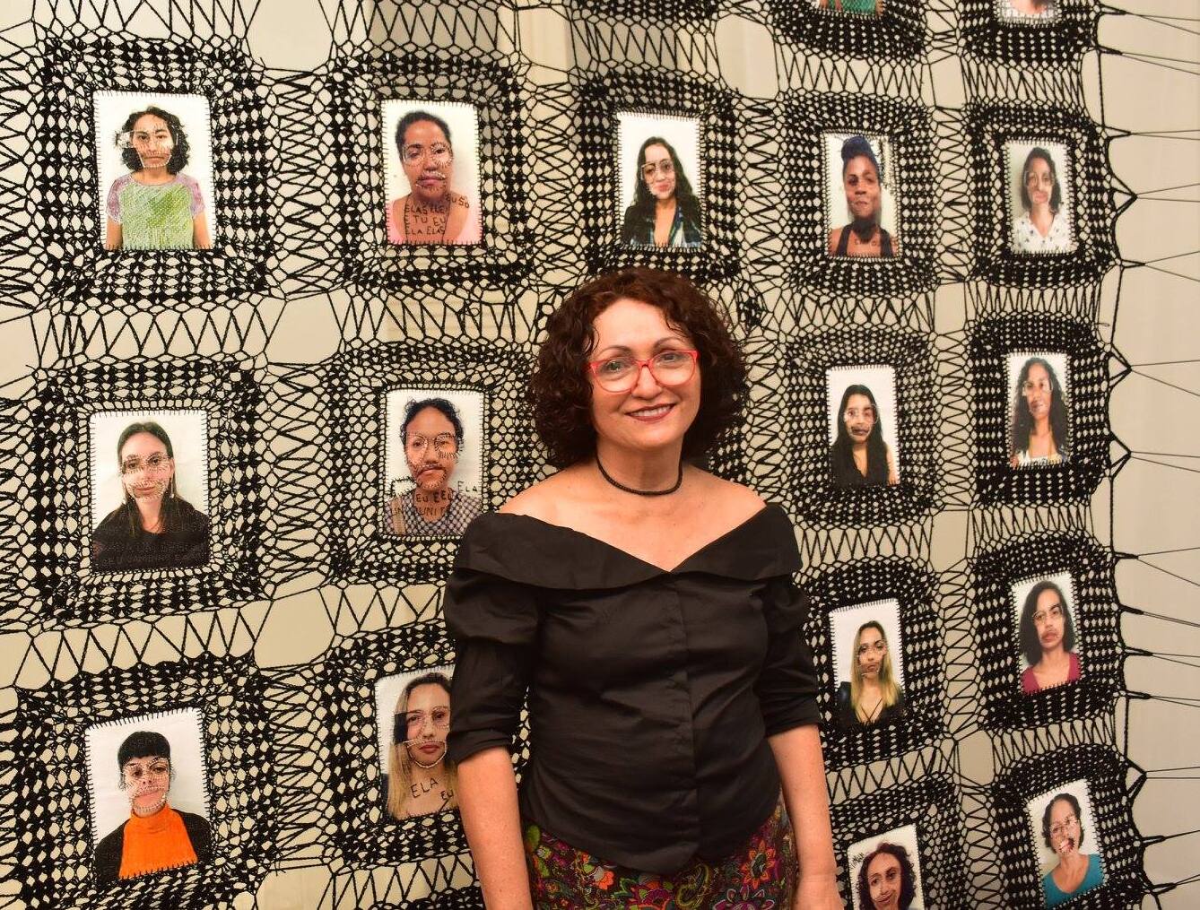 Foto da artista Marlene Barros na frente de uma de suas obras 