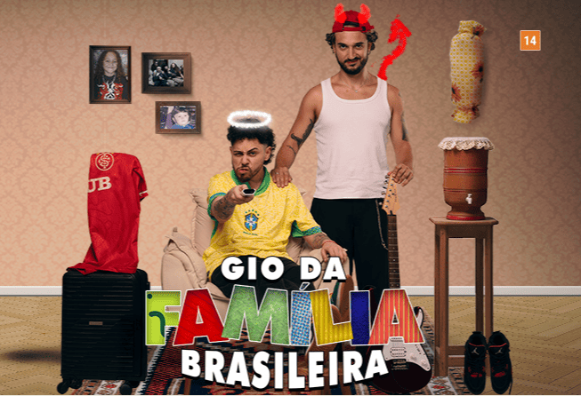 Cartaz do espetáculo "Gio da Família Brasileira" (classificação 14 anos). Em um cenário doméstico, dois homens estão ao centro: um sentado com a camisa da seleção e auréola de anjo, e outro em pé atrás dele com chifres e rabo de diabo. O ambiente é decorado com ícones do cotidiano brasileiro, como filtro de barro, quadros de família, violão e uma mala com camisa de time.