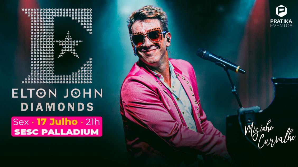 Artista Mizinha Carvalho. Homem sorridente, usando óculos chamativos e blazer rosa, toca piano e canta ao microfone sob luzes de palco.