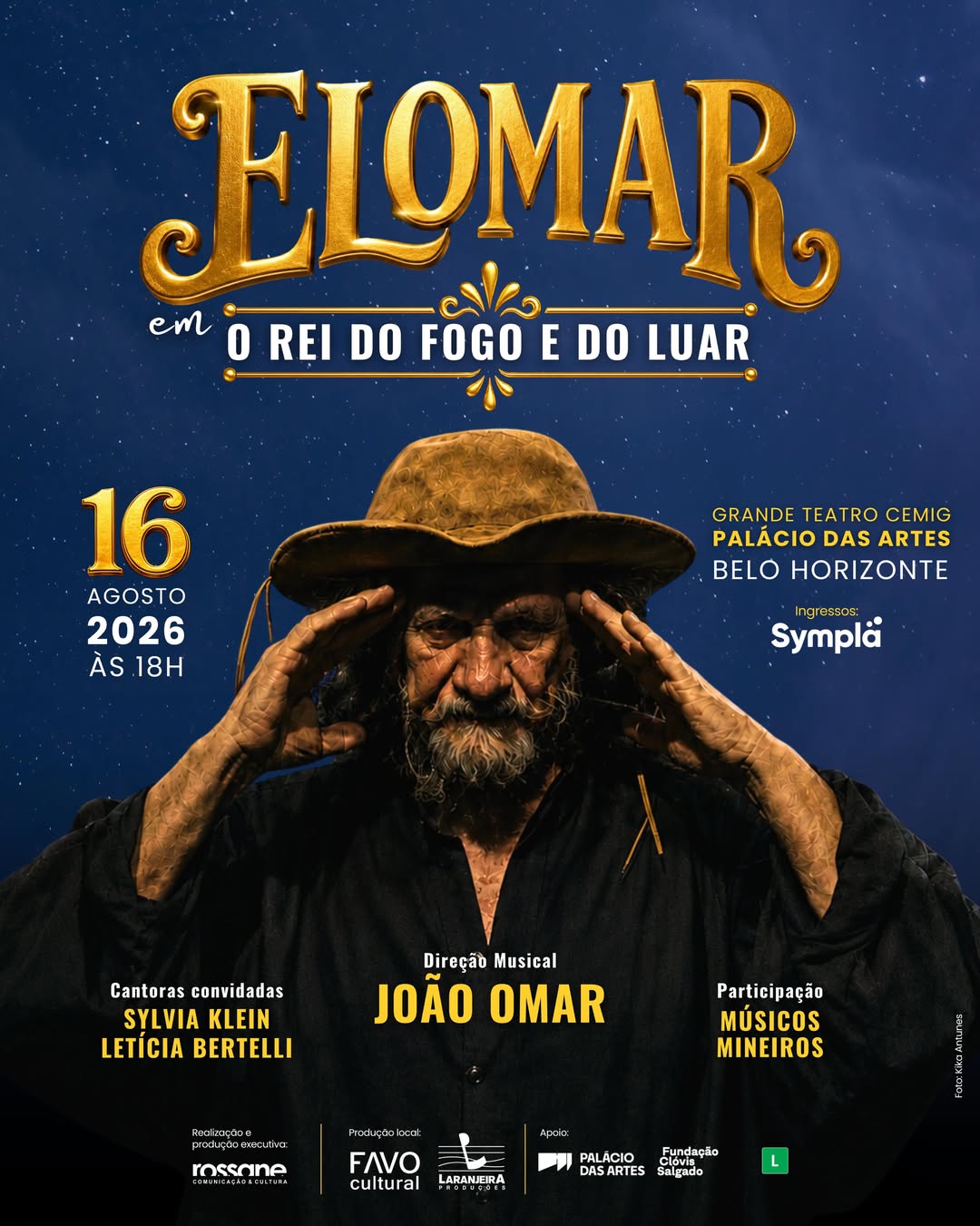Cartaz promocional com fundo azul-escuro estrelado. No centro, há o retrato de Elomar, um homem idoso, de pele bronzeada e enrugada, com barba e bigode grisalhos. Ele veste camisa preta, chapéu de couro e está com as duas mãos erguidas próximas à testa. No topo, em grandes letras douradas, destaca-se o nome "ELOMAR em O REI DO FOGO E DO LUAR". À esquerda, as informações da data: "16 AGOSTO 2026 ÀS 18H". À direita, o local do evento: "GRANDE TEATRO CEMIG PALÁCIO DAS ARTES, BELO HORIZONTE" 