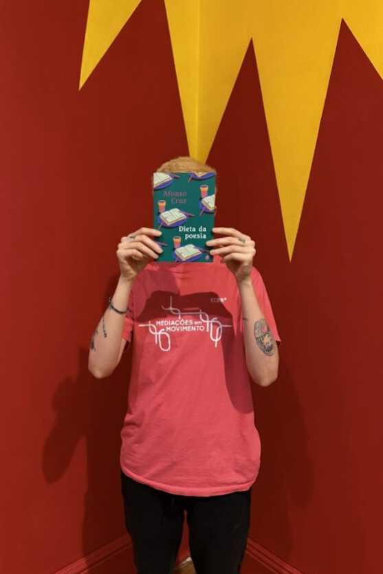 Foto de uma pessoa segurando um livro na frente do rosto 