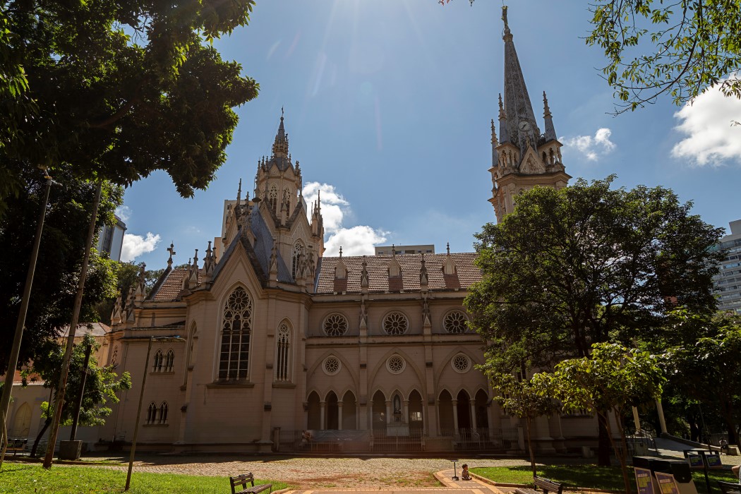 Pablo Gomide/Quarteto Filmes A Igreja de Nossa Senhora da Boa Viagem, uma construção alta e imponente em estilo gótico. O edifício é de cor bege e possui uma fachada rica em detalhes arquitetônicos. No topo, há duas torres altas e pontiagudas. A fachada possui um grande vitral e várias janelas redondas. Em frente à igreja, há um gramado verde e um caminho de tijolos.