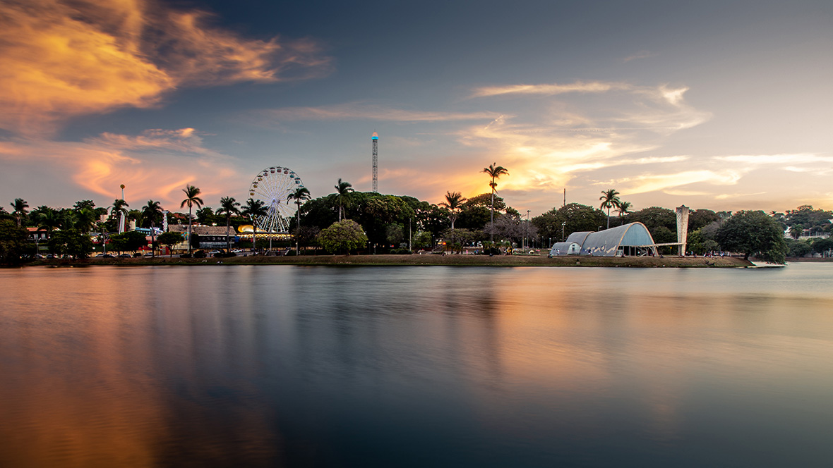 Foto da pampulha com a igrejinha São Francisco e parque guanabara ao fundo