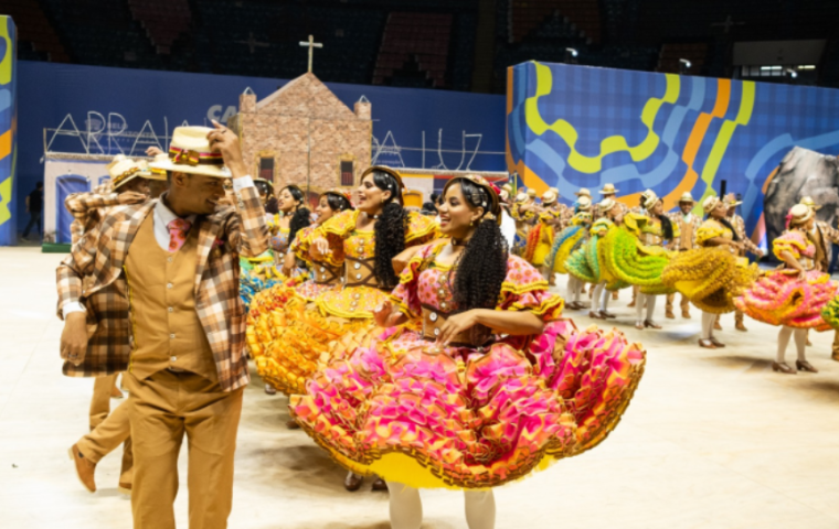 Apresentação de um grupo de quadrilha dançando, com um casal em destaque.