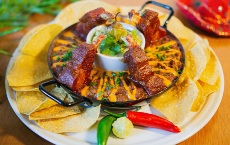 Prato com comida mexicana ao centro, nachos em volta e pimenta