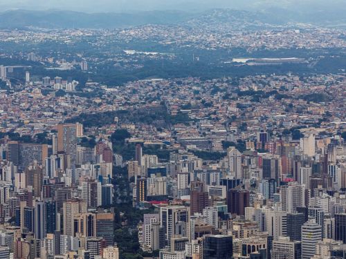 Panorâmica da cidade de Belo Horizonte vista no Parque Serra do Curral. Muitos edíficios, áreas verdes e o Estádio Mineirão ao fundo.
