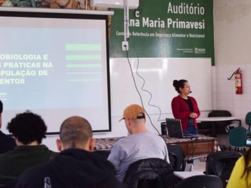 Imagem de uma pessoa apresentando um trabalho a frente de um sala de aula