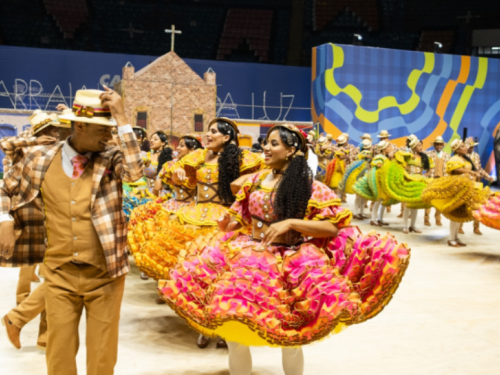 Apresentação de um grupo de quadrilha dançando, com um casal em destaque.