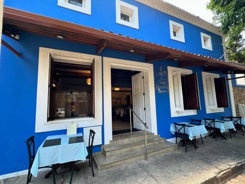 Fachada do Restaurante Casa Piacere com paredes azuis, portas e janelas brancas 