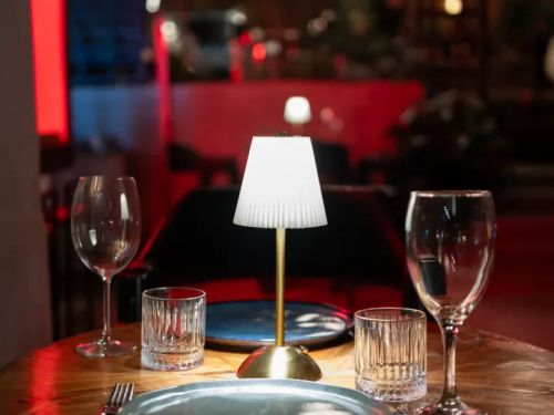 Foto da mesa pronta com um mini abaju centralizado, taças e pratos postos 