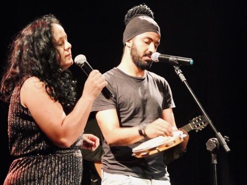 Imagem com duas pessoas cantando (uma segura um pandeiro)