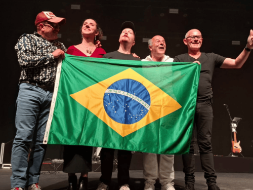 Imagem de quatro homens e um mulher segurando a bandeira do Brasil