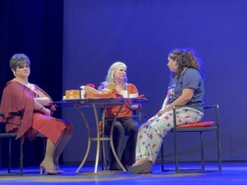 Duas mulheres e uma adolescente sentadas à mesa