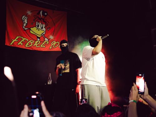 Imagem de dois homens com o rosto tampado, cantando.