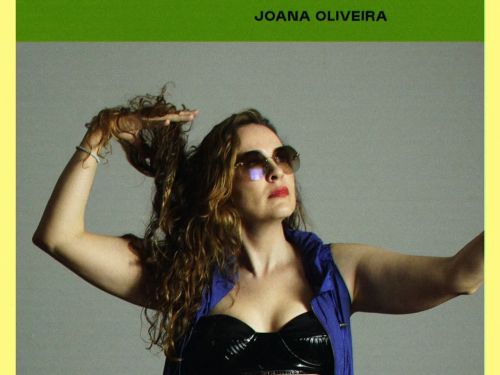 Mulher de óculos escuro, colete azul e top preto