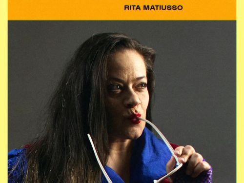 Mulher segurando óculos entre os lábios e com blusa de frio azul