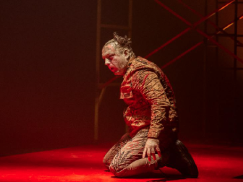 Imagem de um homem ajoelhado, com maquiagem de machucados 