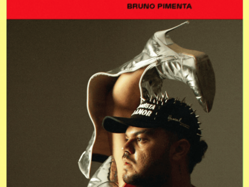 Homem com boné preto, blusa vermelha e segurando uma bota de salto prateada