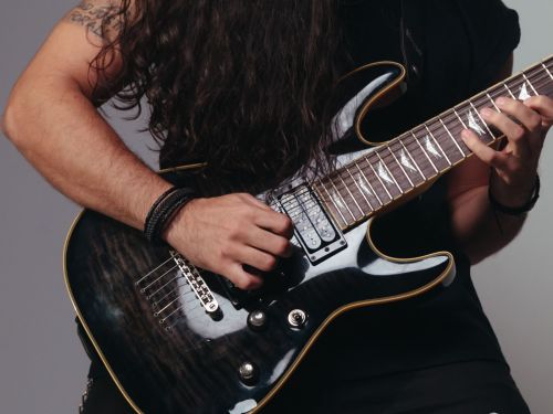 zoom na mão de um homem tocando guitarra 