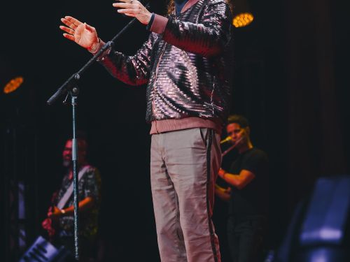 Alceu Valença em pé cantando com as mão erguidas 