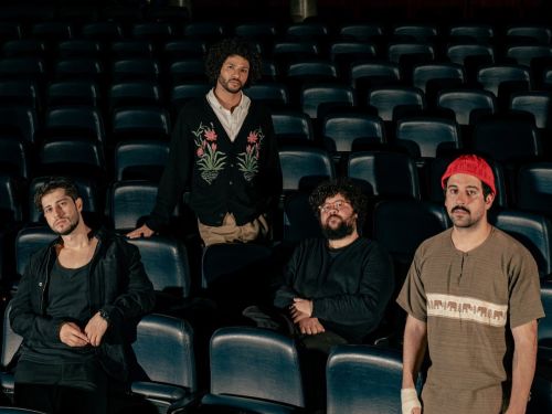 Foto da banda Zimbra, 4 integrantes no cenário de uma sala de cinema