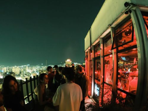 Imagem de varias pessoas em um festa com vista para a cidade a noite 