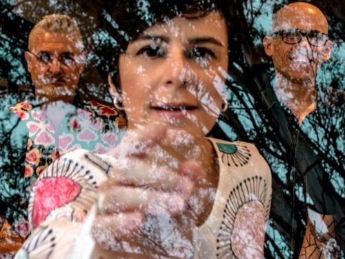 uma mulher no centro apontando e dois homens ao lado 