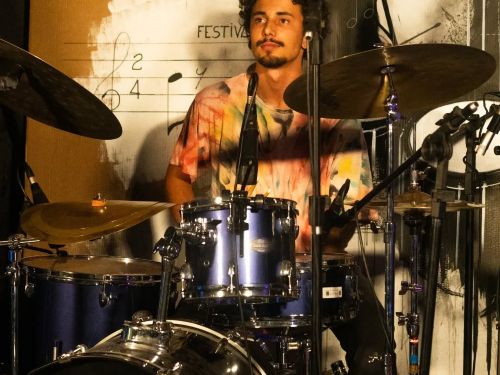 um homem tocando bateria em um lugar bem iluminado