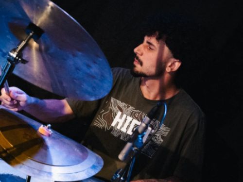 um homem tocando bateria em um ambiente escuro