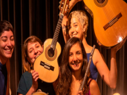 Imagem real de quatro mulheres posando para foto segurando violão e flauta