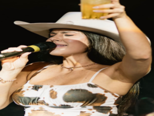 Imagem de uma mulher cantando no microfone com um copo na mão 